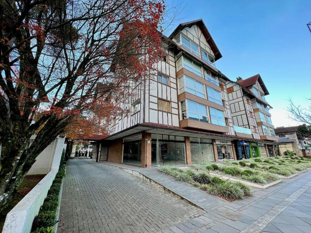 un edificio en una calle frente a un árbol en Apartamentos Gartenberg no CENTRO by Achei Gramado, en Gramado