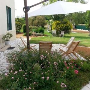 - une terrasse avec 2 chaises, un parasol et des fleurs dans l'établissement Maison de famille Benaiteau à 10' du Puy du Fou, à Puy-du-Fou
