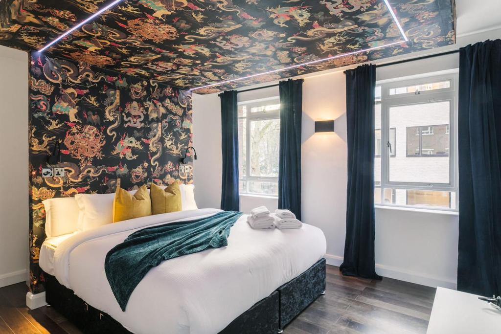 ロンドンにあるWelcomeStay Fitzrovia Two Bed Apartments - Sleep in Opulent Luxuryの花柄の壁紙を用いたベッドルーム1室(大型ベッド1台付)