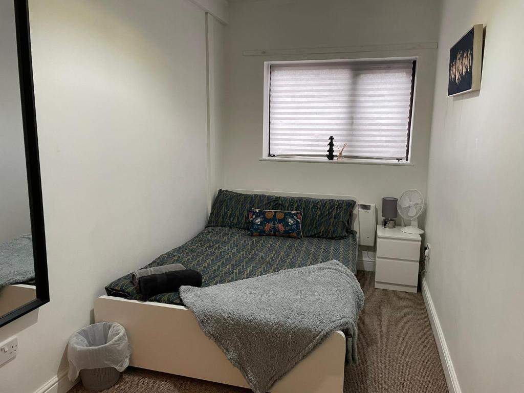 a small bedroom with a bed and a window at Spacious sofa bed lounge area with ensuite bedroom in Wednesbury