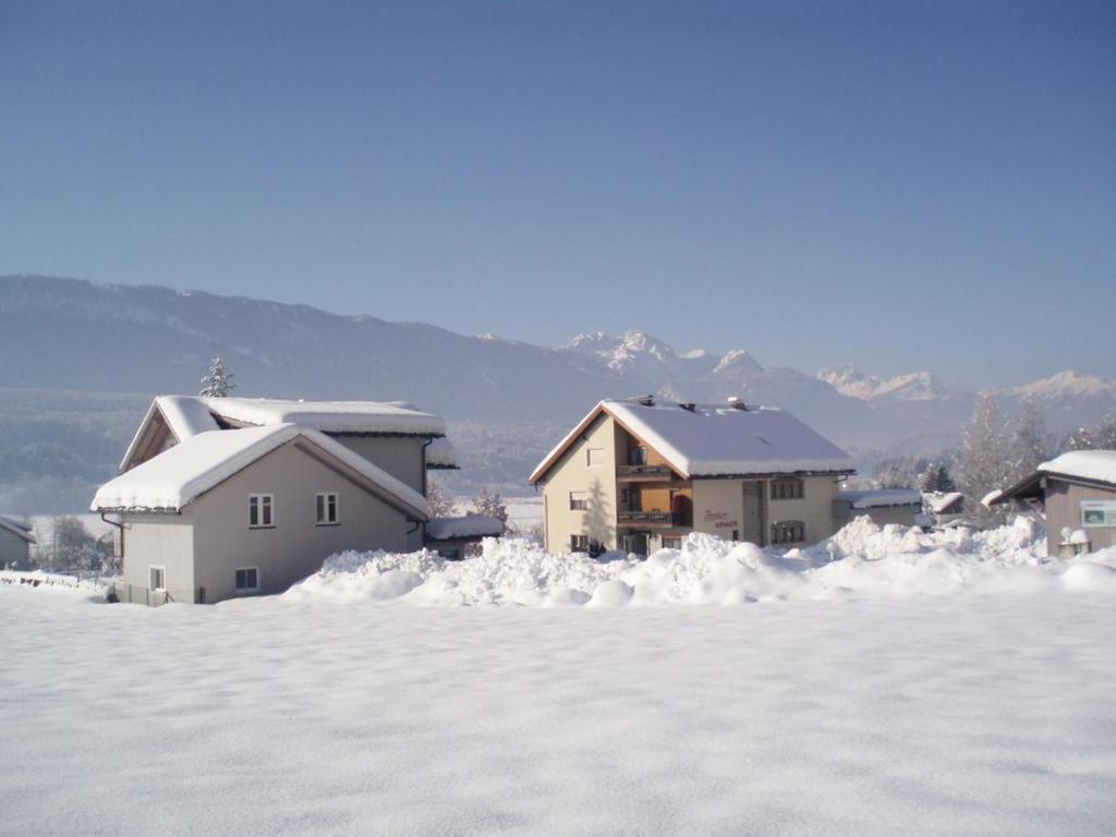 a group of houses covered in snow with mountains in the background at Appartementhaus Kraker in Presseggersee