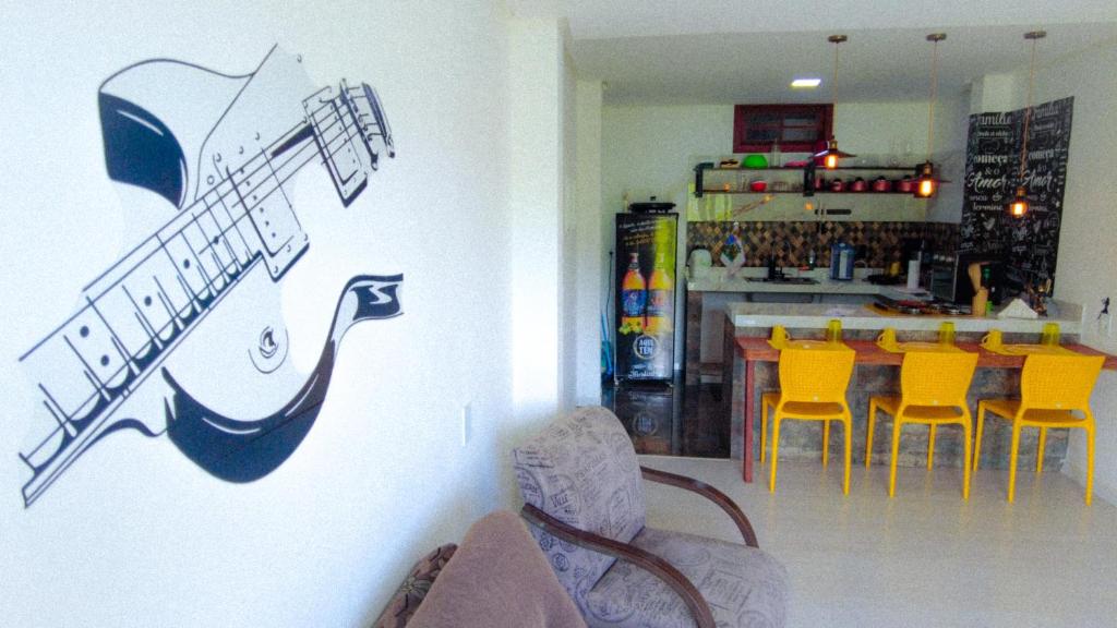 ein Restaurant mit einer Gitarre an der Wand und gelben Stühlen in der Unterkunft Casa no Caravaggio ao lado da cervejaria 3 Santas in Santa Teresa