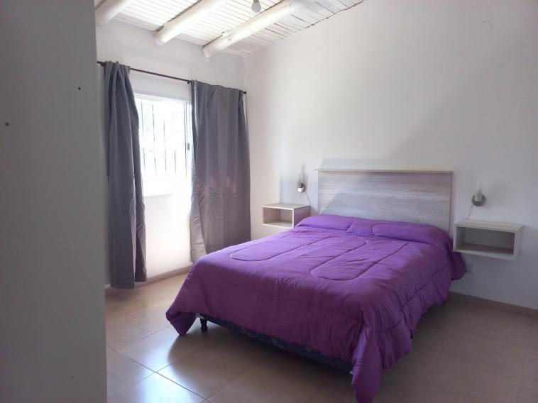 1 dormitorio con cama morada y ventana en Cabañas Vista Andes IV en Luján de Cuyo