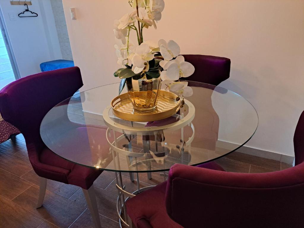una mesa de cristal con un jarrón con flores. en Relax moderna tiny suite, en Manta