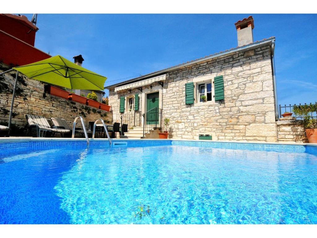 a swimming pool in front of a house with an umbrella at Casa Antignana in Tinjan