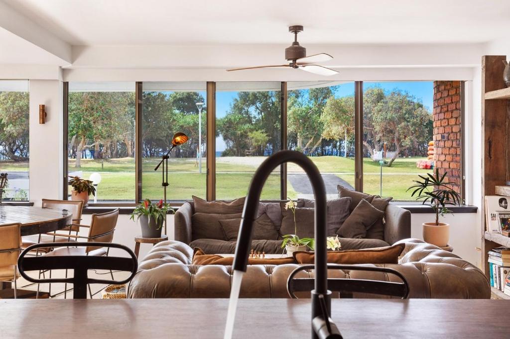 a living room with a couch and a large window at Byron Pacific Apartments - On Clarkes Beach in Byron Bay