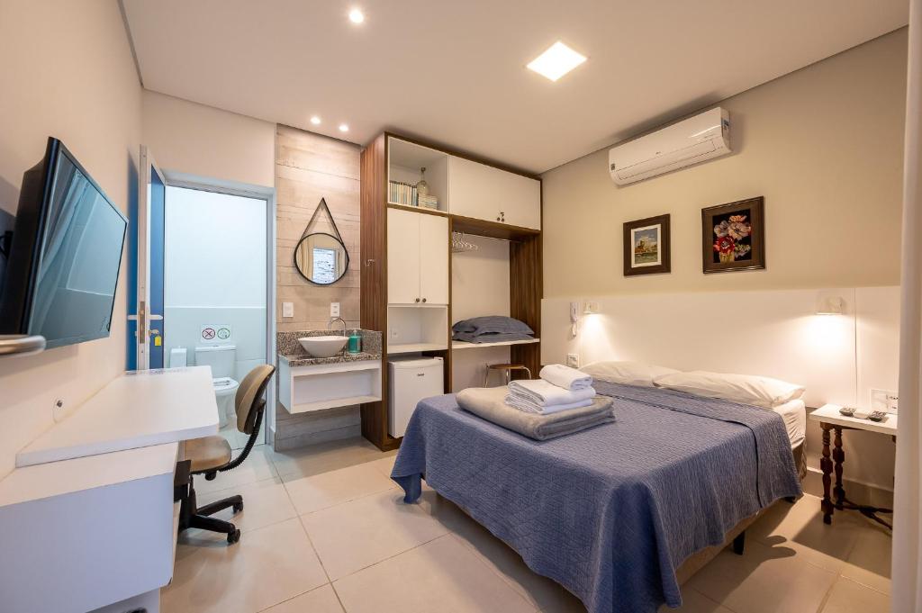 a bedroom with a bed and a desk and a sink at K2 Residence in Campinas