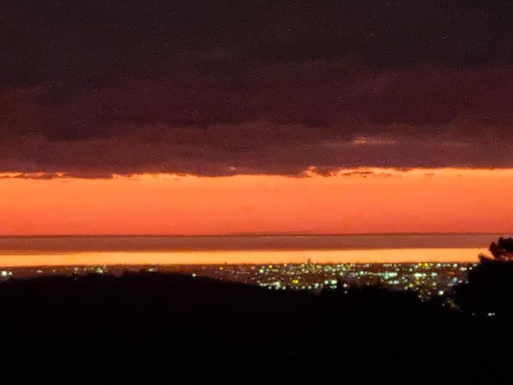a sunset over the ocean with a city in the distance at Sunset Hues -Enjoy Peace & Nature in Norton Summit