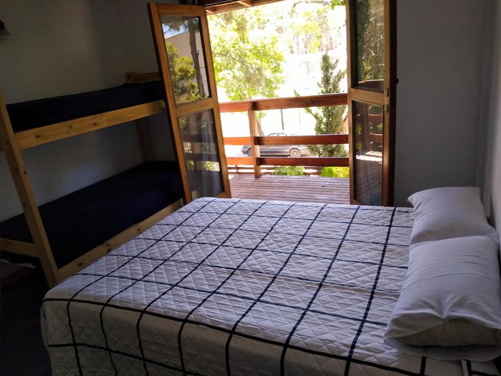 1 dormitorio con cama y ventana grande en cabañas del bosque en Pinamar