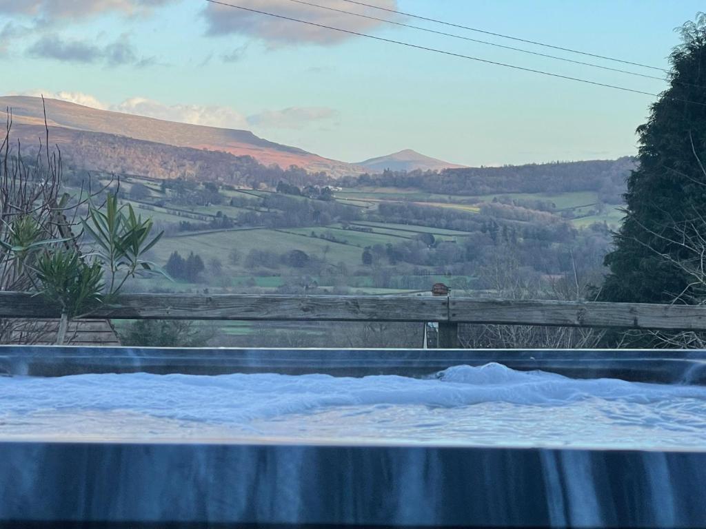 a hot tub with a view of a mountain at Peacock Cottage, Coity Bach in Talybont