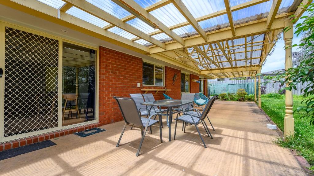 a patio with a table and chairs under a roof at Serrell by the Sea in Inverloch