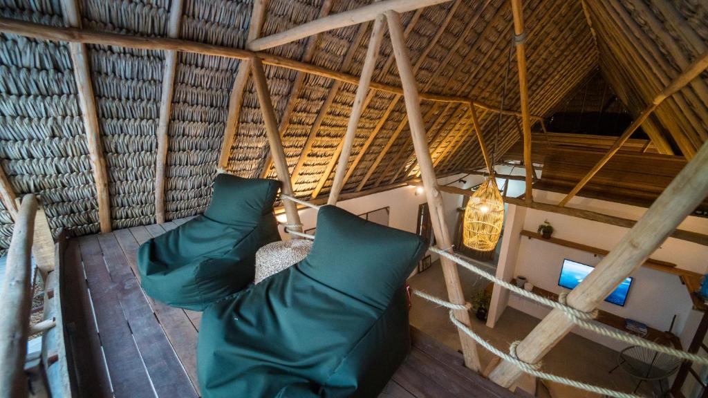 um quarto no sótão com almofadas verdes num telhado de palha em Jandaia Atins em Atins