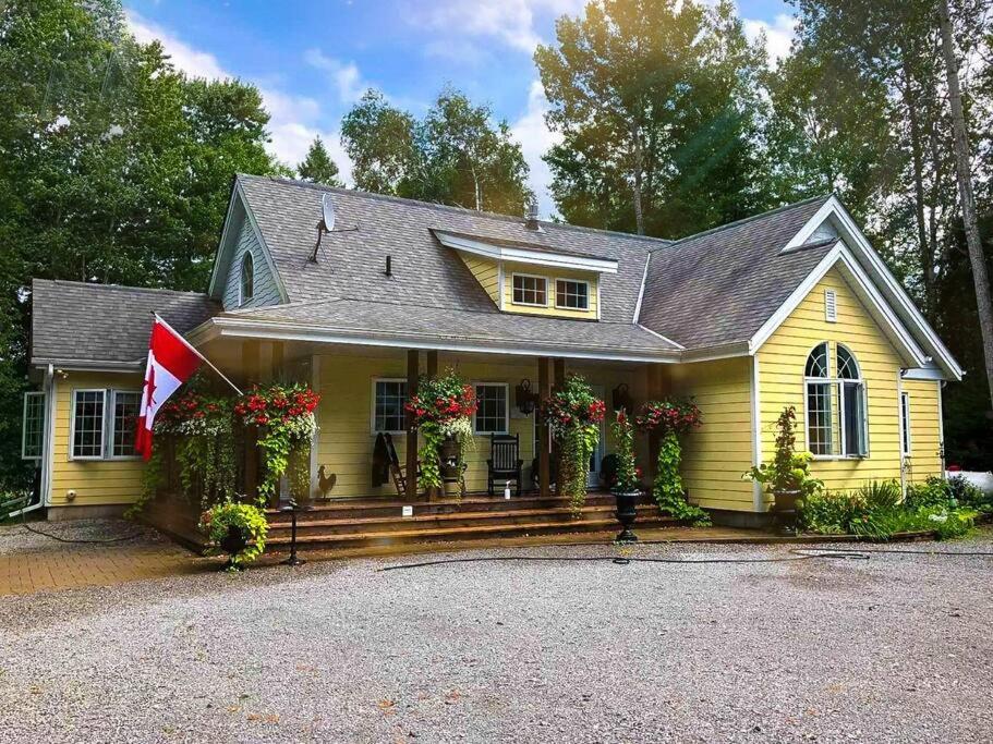 a yellow house with a flag in front of it at WELCOME TO BURNT RIVER ESTATE in Kawartha Lakes