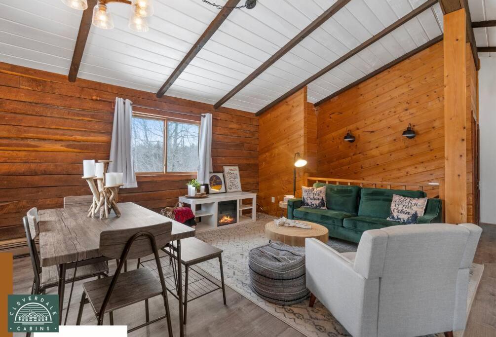 a living room with a green couch and a table at Cozy Cabin at Cloverdale Cabins in Hinckley