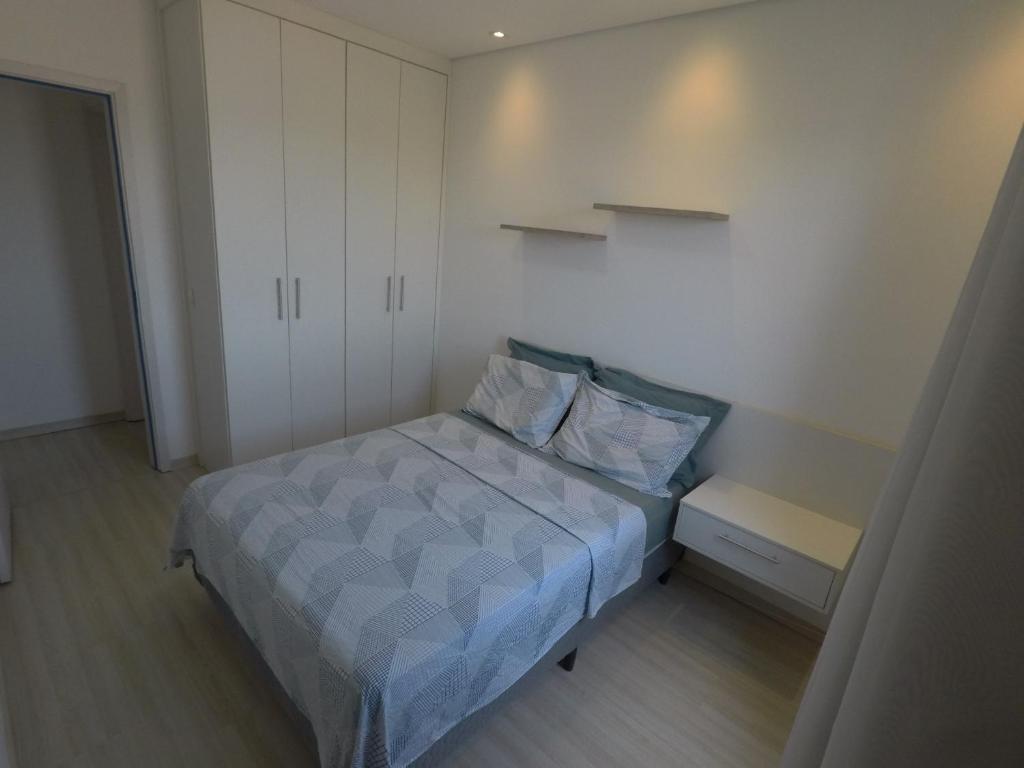 um pequeno quarto com uma cama e um armário branco em Apê aconchegante e seguro em Salto