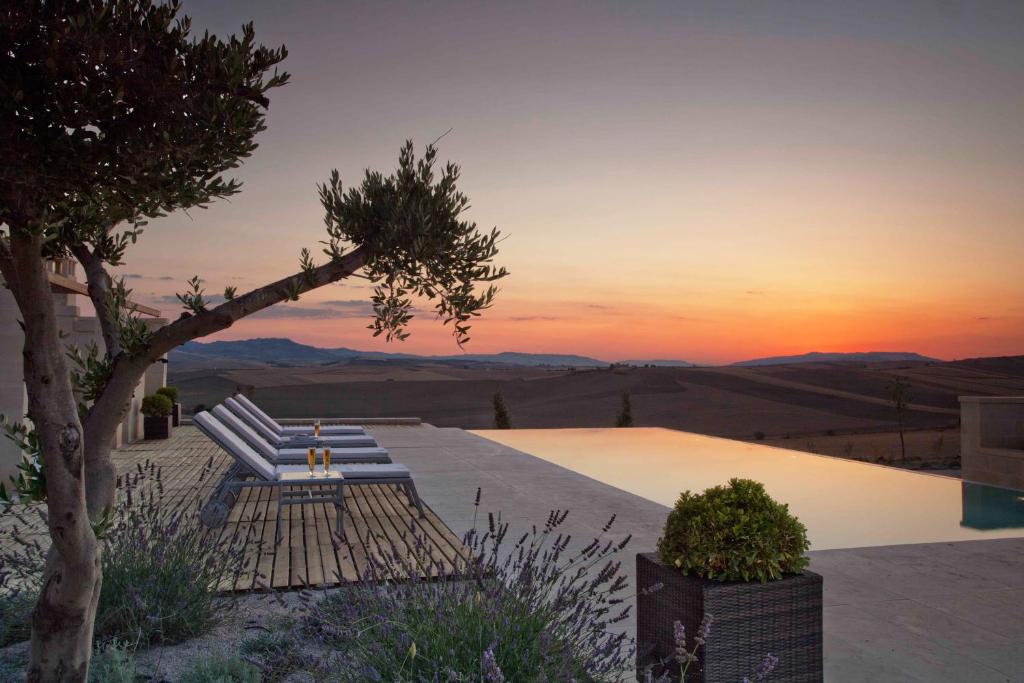 una piscina con tumbonas y un árbol con puesta de sol en Villa Matera, en Matera