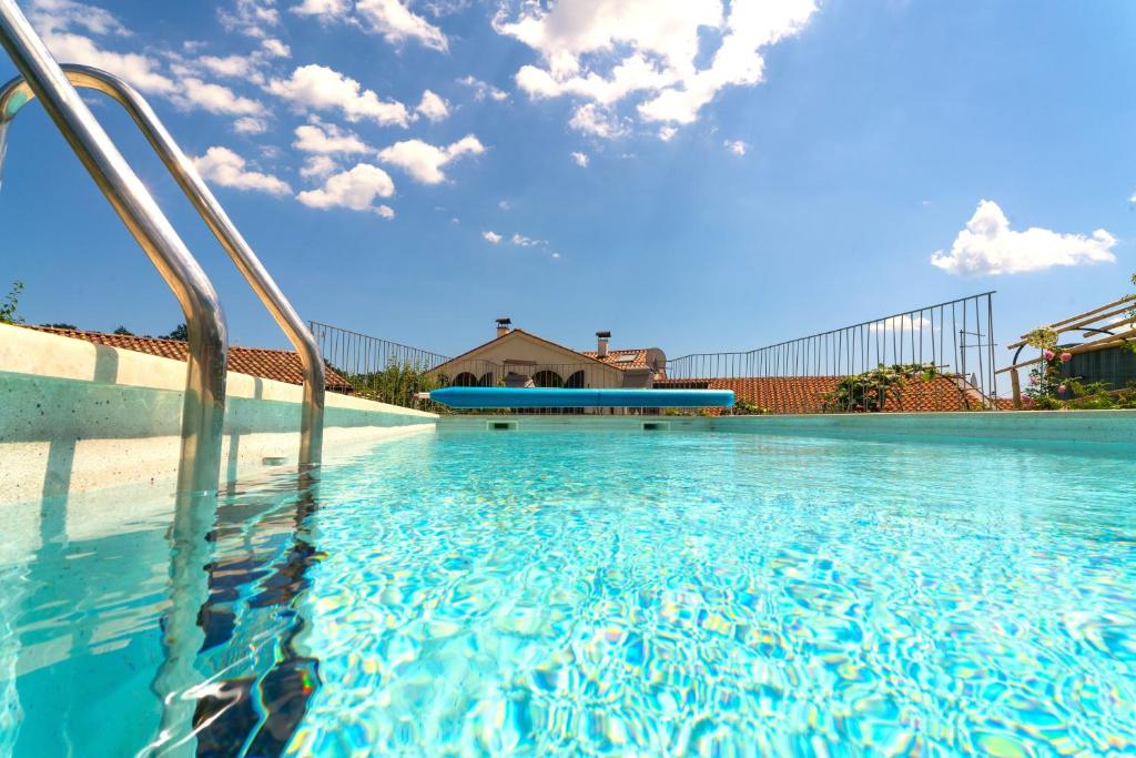a swimming pool with blue water and a house at Villa Salvia with pool in Ružići