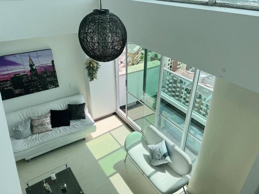 uma sala de estar com um sofá e uma grande janela em Beautiful 1 Br Loft Apartment em Manizales
