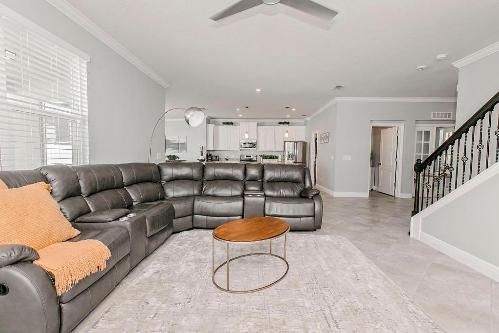 a living room with a leather couch and a table at Spacious 4 Bed Home near Orlando Gated Pool Access in Sanford