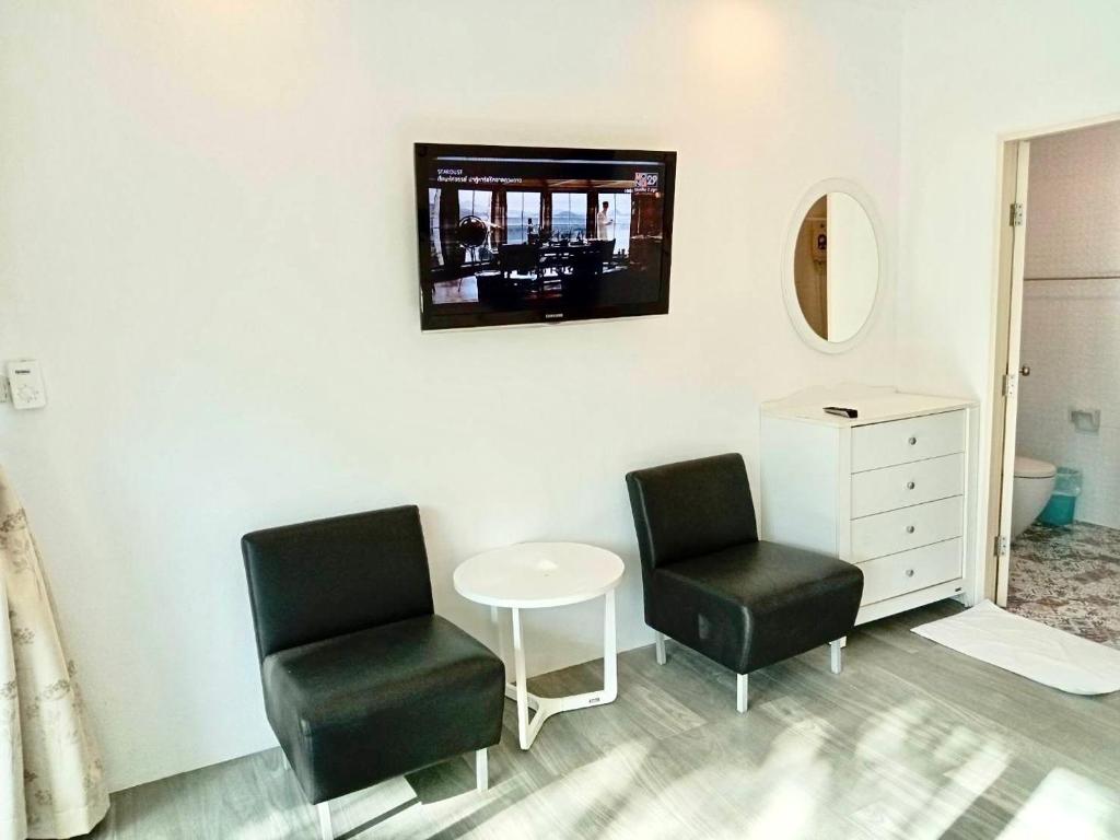 a room with two chairs and a tv on a wall at Garden Home Kata in Kata Beach