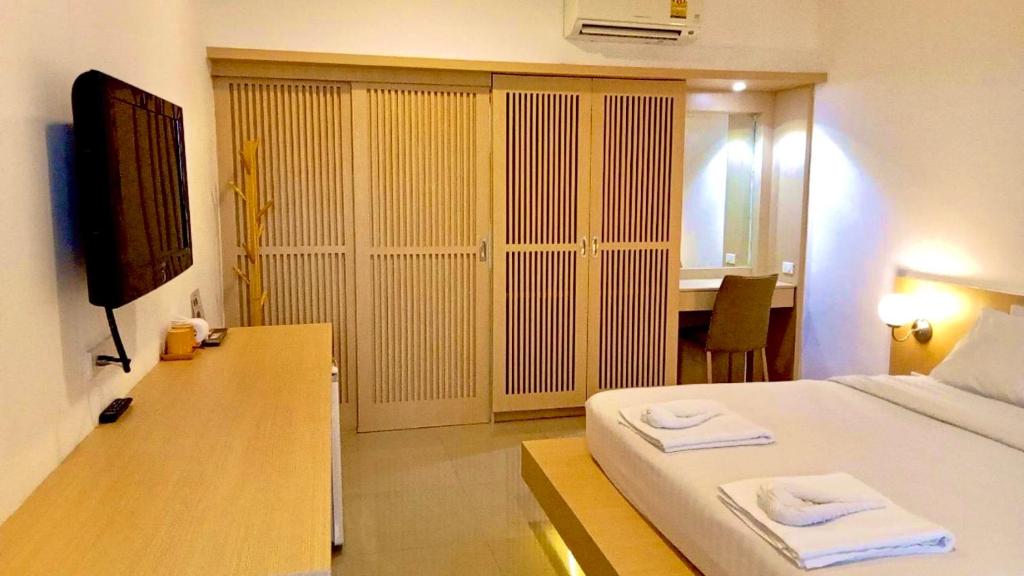 a bedroom with a bed and a desk with a television at Garden Home Kata in Kata Beach