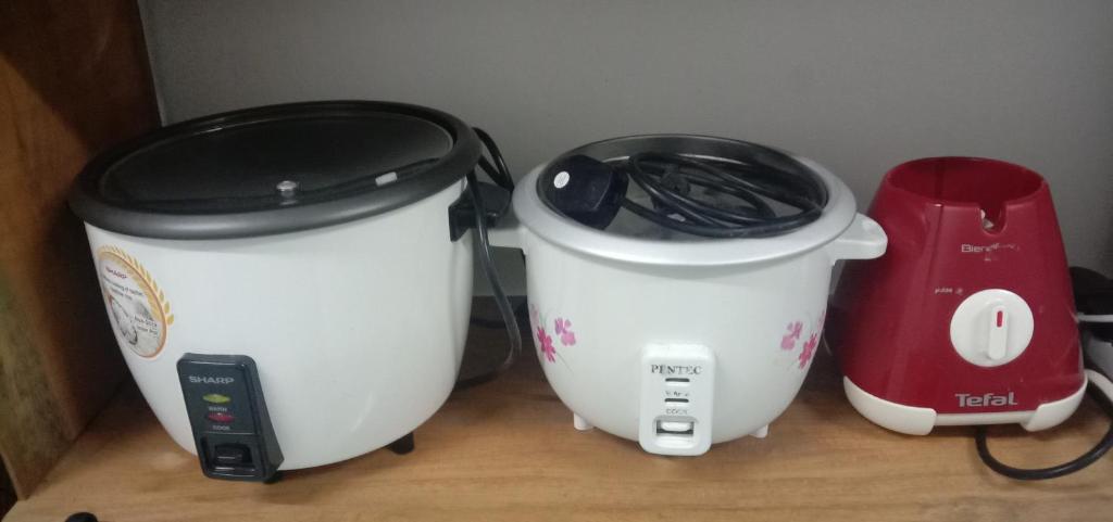two white crock pots sitting on a counter with a red appliance at AZhomestay in Jitra