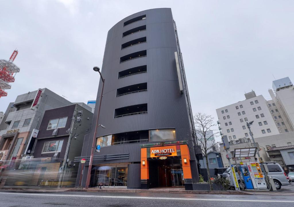 a tall grey building on a city street at APA Hotel Koriyama Ekimae in Koriyama