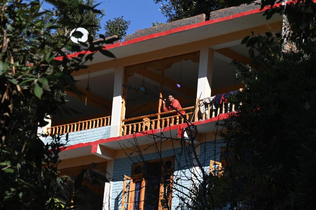 um homem na varanda de uma casa com uma bola de futebol em MOZO Inn&Cafe Jibhi em Banjār