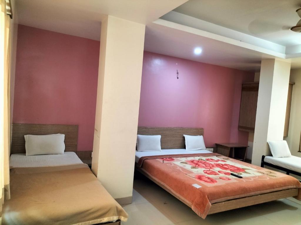 2 Betten in einem Zimmer mit rosa Wänden in der Unterkunft HOTEL SAI SURYA in Shirdi