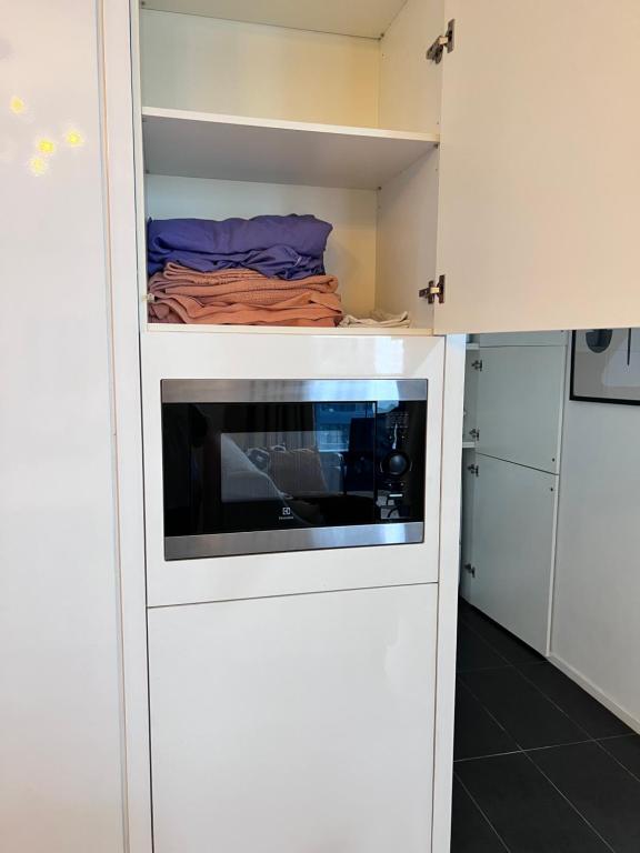 eine kleine Küche mit einer Mikrowelle in einem weißen Schrank in der Unterkunft New Arcoris Mont Kiara Huge Balcony for 8 pax 2 BR -Garden- in Kuala Lumpur