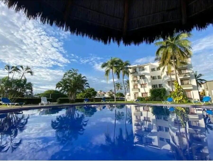 ein Pool mit Palmen und ein Gebäude in der Unterkunft Magnifico Departamento, cocina equipada, 2 Recamaras 2 Baños , hasta 6 Personas, 3 albercas, playa a 50 mts wifi, aire acondicionado in Manzanillo