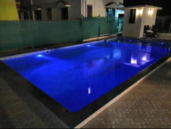 a large blue swimming pool in a house at Anant Resort Nagaon Beach Walking Distance 2min Alibaug in Alibaug