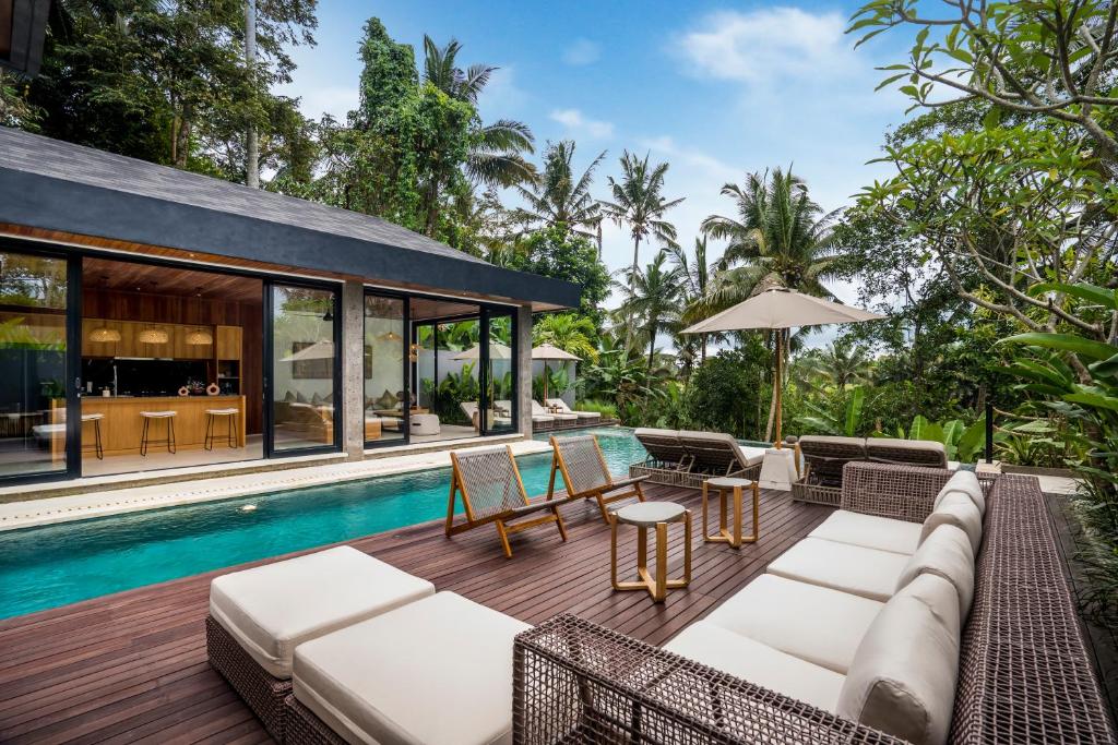 an outdoor patio with a couch and chairs next to a pool at Villa Livia by BaliSuperHost in Ubud
