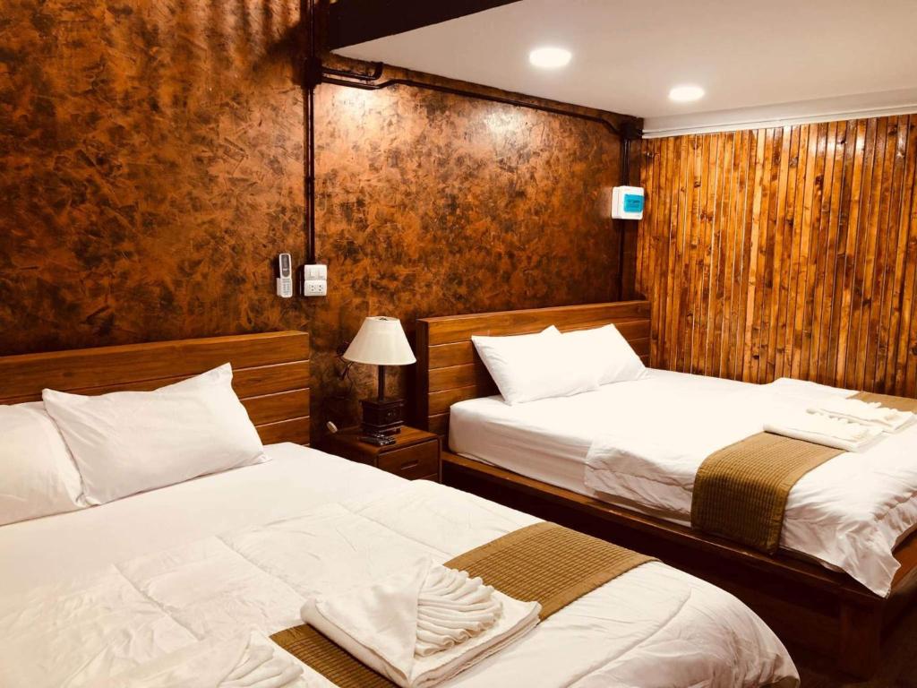 - 2 lits dans une chambre dotée de murs en bois dans l'établissement กอบสุข รีสอร์ท2 k13, à Ban Ton Liang