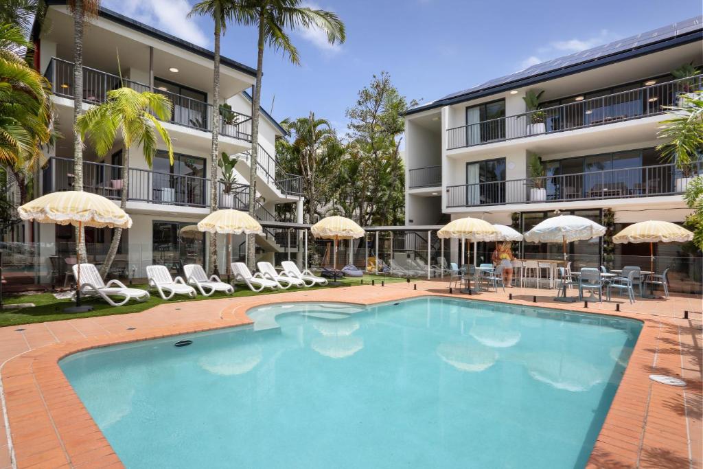 a swimming pool in front of a building at Abode Mooloolaba, Backpackers & Motel rooms in Mooloolaba