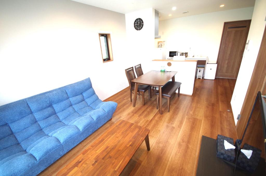 uma sala de estar com um sofá azul e uma mesa em Plage Garden Place　A-101 em Miyako Island