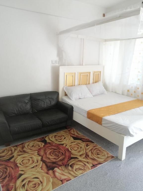 1 dormitorio con 1 cama y 1 sofá sobre una alfombra en Mombasa City Center Studio en Mombasa