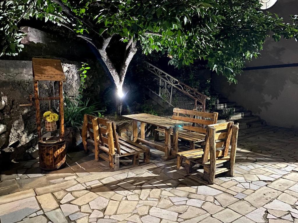 une table et des chaises en bois assises à côté d'un arbre dans l'établissement EleGaya Guest house, à Ijevan