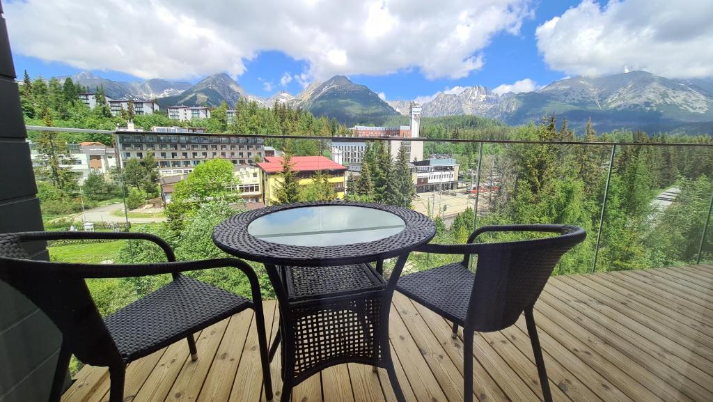 een tafel en 2 stoelen op een balkon met uitzicht op de bergen bij Unique View Design Apartment Štrbské Pleso in Štrbské Pleso