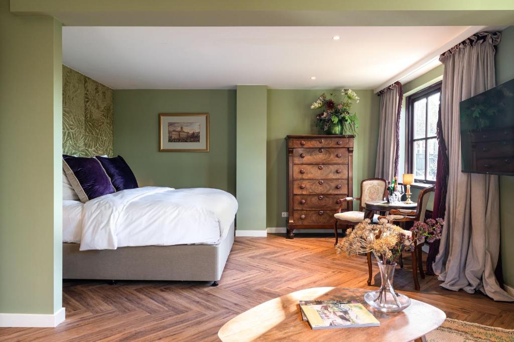 1 dormitorio con paredes verdes, 1 cama y 1 mesa en Boetiekhotel De Kastanjehof en Lage-Vuursche