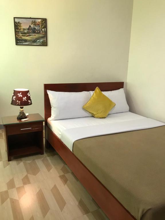 Una cama con una almohada amarilla y una lámpara sobre una mesa en Drew Hostel en Tagbilaran City