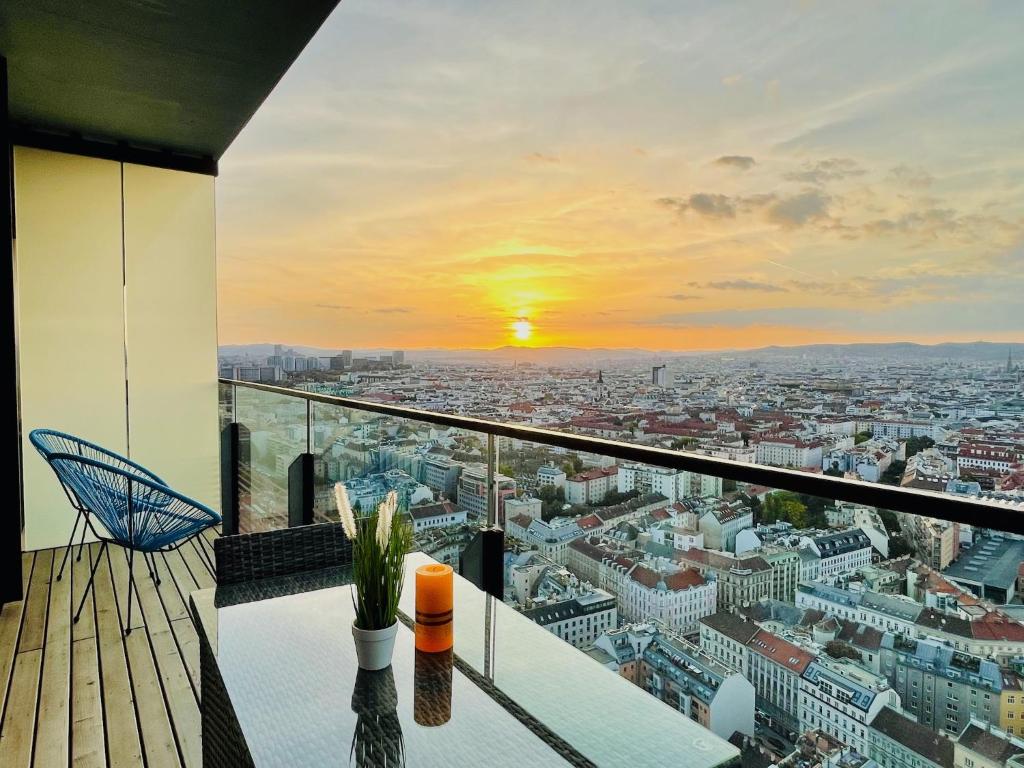 a balcony with a view of a city at sunset at TrIIIple Level 31 - Sonnenwohnen Apartment mit fantastischem Ausblick und Parkplatz in Vienna