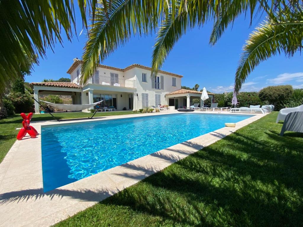 einen Pool vor einem Haus mit Palmen in der Unterkunft Villa Les Cycas - GRI170 by Interhome in Grimaud