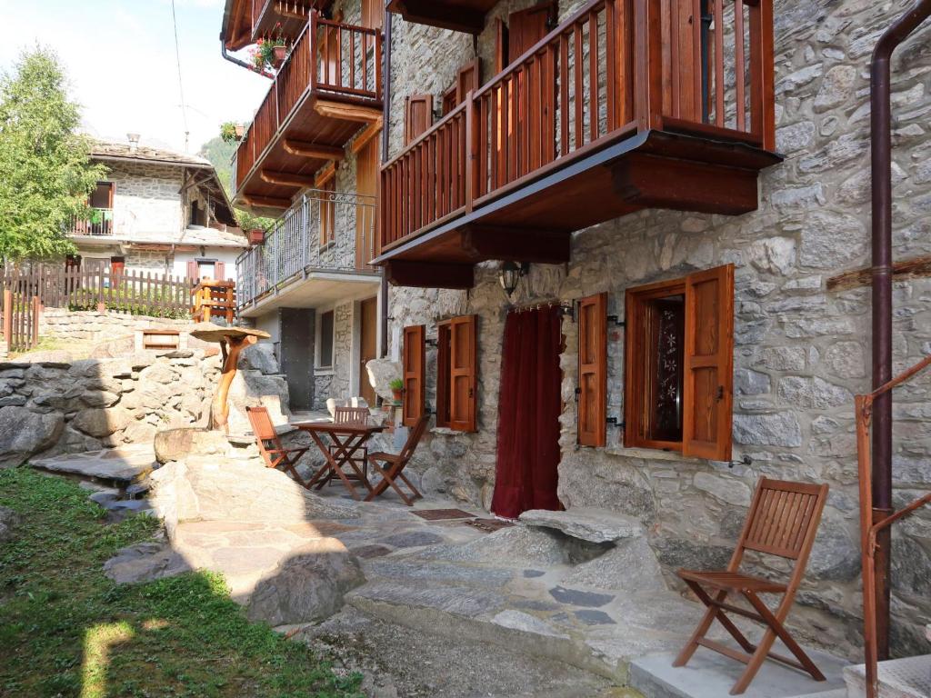 een stenen huis met een balkon en een tafel en stoelen bij Holiday Home Casa Ivan by Interhome in Noasca