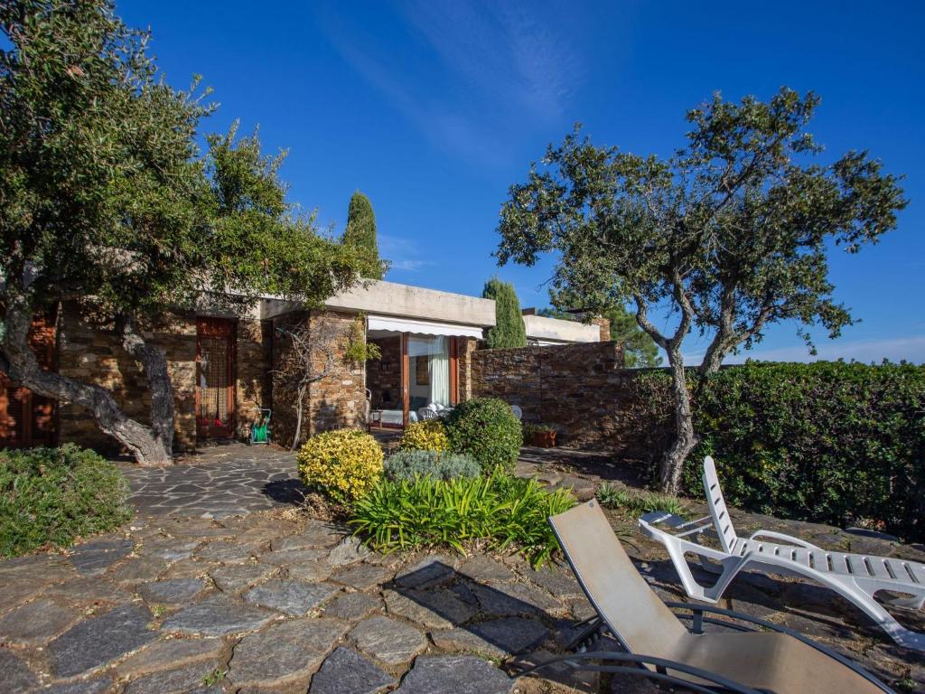 a stone house with two white chairs in a yard at Holiday Home Village Les Fourches by Interhome in Cabasson