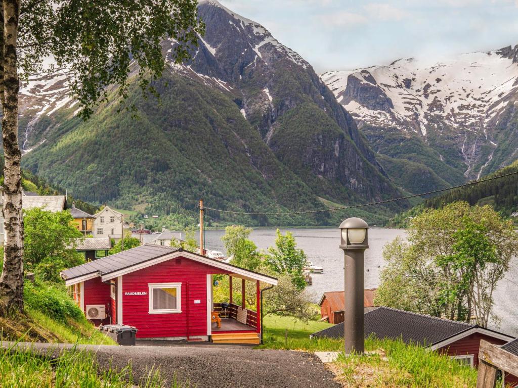 a small red house with a mountain in the background at Holiday Home Raumelen - FJS018 by Interhome in Balestrand