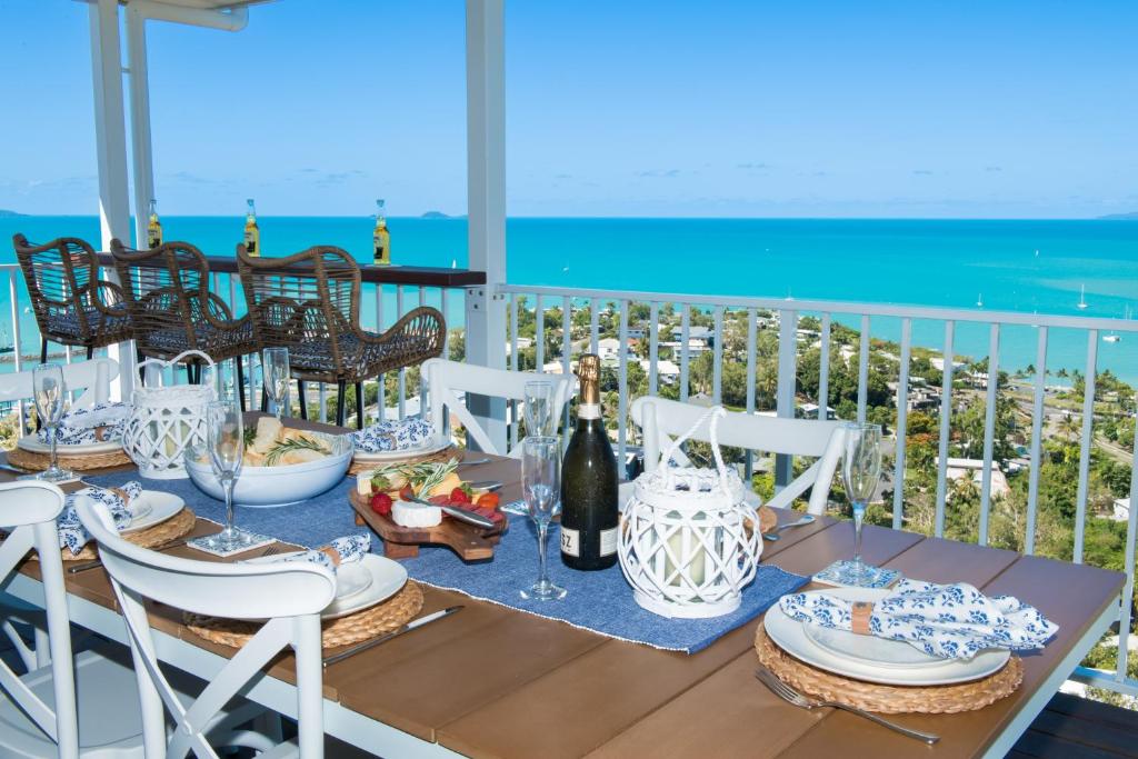 Airlie Beach的住宿－South Hamptons Beach House，阳台上的餐桌上摆放着食物和葡萄酒