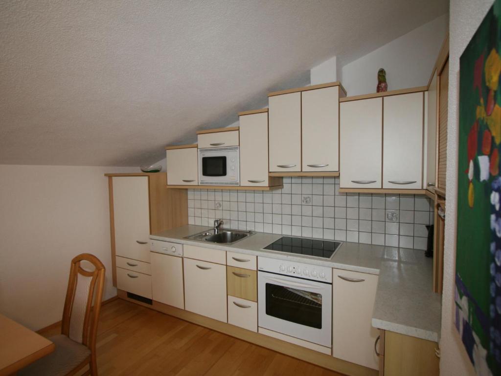 eine kleine Küche mit weißen Schränken und einem Waschbecken in der Unterkunft Apartment Neurauter - FGZ156 by Interhome in Fügen