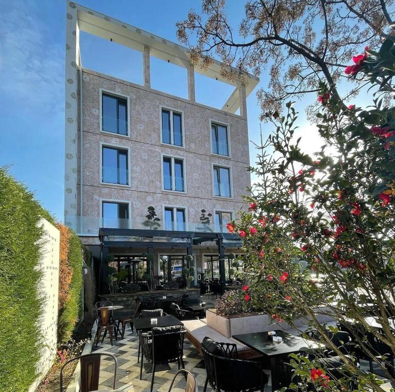 a building with tables and chairs in front of it at Nord Hotel Boutique in Shkodër