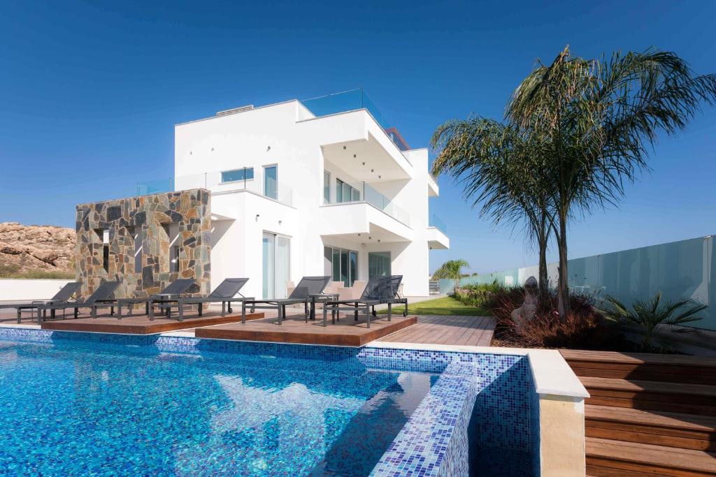 a white house with a swimming pool in front of it at Sea Pearl Beachfront Villas - Breeze in Ayia Napa